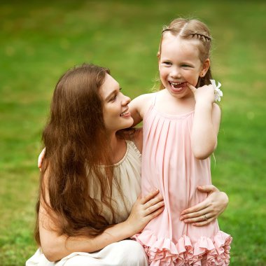 Anne ve kızı parkta birbirlerine sarılıp oynuyorlar.