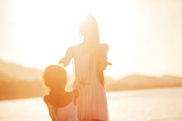 Äiti ja tytär onnellisia auringonlaskun aikaan — kuvapankkivalokuva