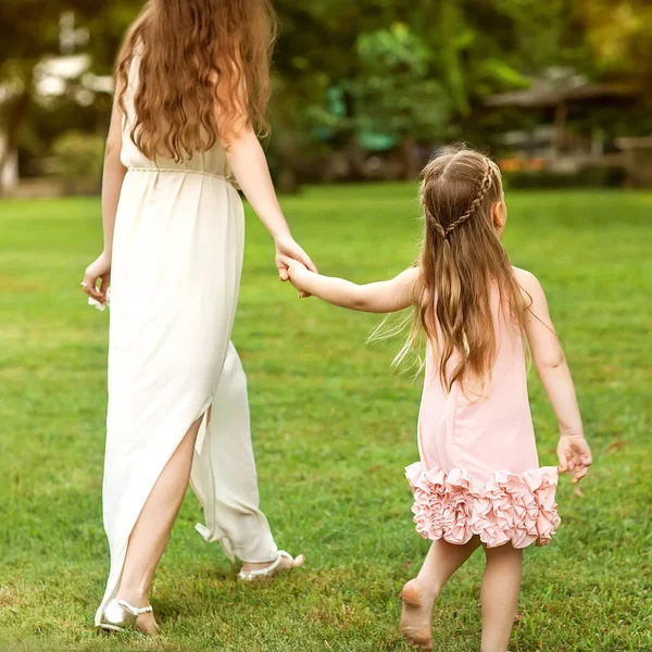 Mãe e filha andando no parque de mãos dadas no amor — Fotografia de Stock