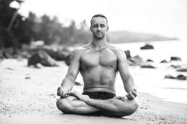 Man praktijk yoga op het strand bij zonsondergang — Stockfoto