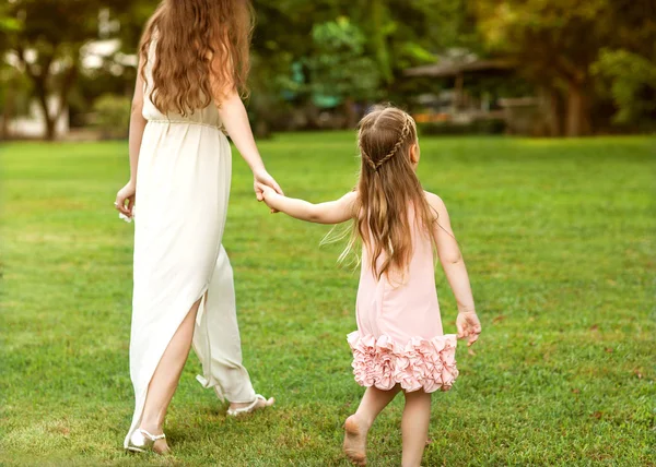 Madre e hija caminando en el parque cogidas de la mano en el amor —  Fotos de Stock