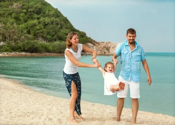 Familia feliz caminando sobre el mar en la playa — Foto de Stock