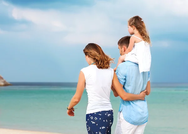 Familia feliz caminando sobre el mar en la playa — Foto de Stock