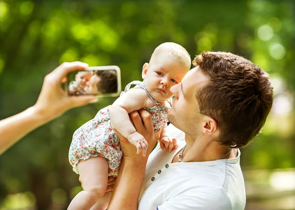Rodina s dítětem v parku s selfie mobilní telefon — Stock fotografie