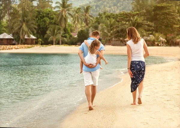 Familia feliz caminando sobre el mar en la playa — Foto de Stock