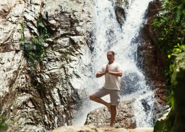 pratik Yoga yakınındaki mountai bir şelale sportif genç adam