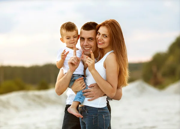 Feliz hermosa familia en la puesta de sol de la playa — Foto de Stock