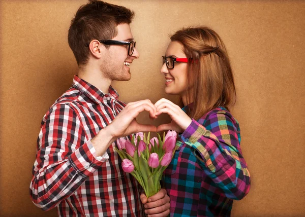 Jovem casal apaixonado fazer um coração e as mãos estão segurando um buque — Fotografia de Stock