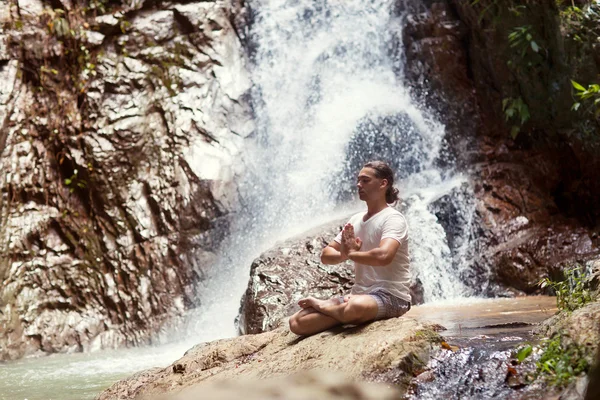 Chico relajado sentado cerca de la cascada . — Foto de Stock