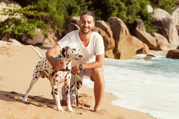Uomo con cane sulla spiaggia tropicale — Foto Stock