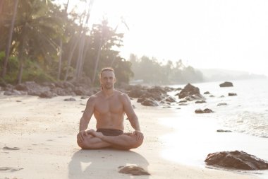 Adam pratik yoga gün batımında sahilde.