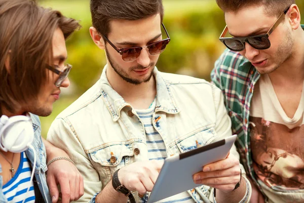 Three young men friends using tablet computer in park — Stock Photo, Image