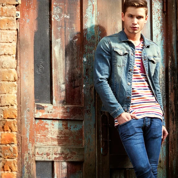 Hipster style guy. Fashion man standing near a wooden door — Stock Photo, Image