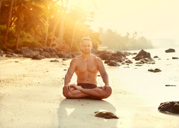 Młody człowiek sprawny praktyk sun zwrot grzecznościowy jogi na plaży w słońca — Zdjęcie stockowe