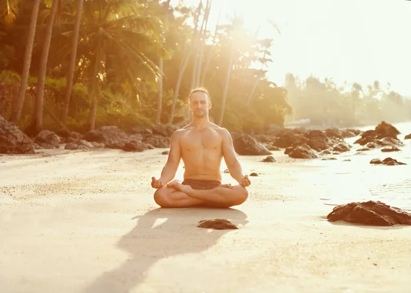 Přizpůsobit mladý muž praxe jógy oslovení slunce na pláži u sluncí — Stock fotografie