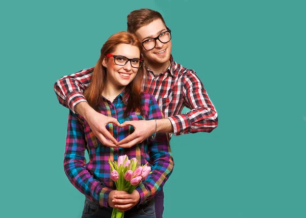 Young couple in love make a heart and hands are holding a bouque — Stock Photo, Image