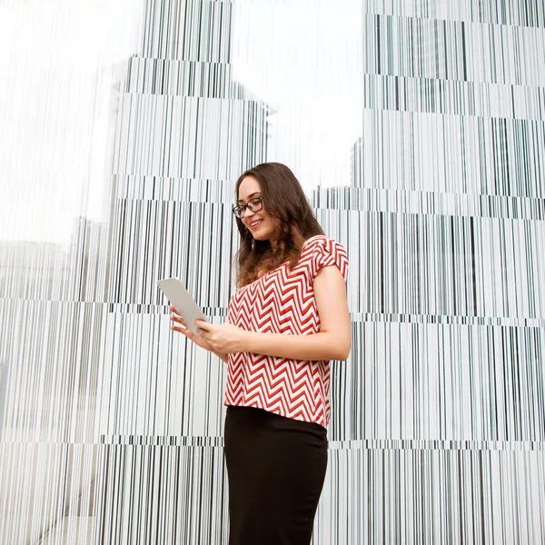 Fashion girl holding a tablet PC on the business background — Stock Photo, Image