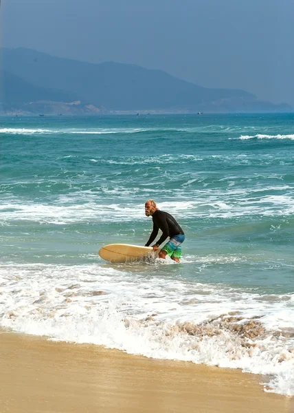 Surfista en el mar está de pie con una tabla de surf de color brillante . — Foto de Stock