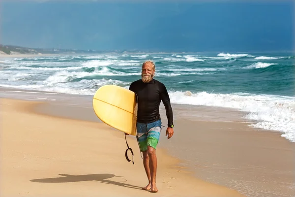Surfeur à la mer est debout avec une planche de surf couleur vive . — Photo
