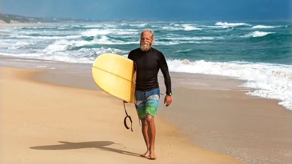 Surfeur à la mer est debout avec une planche de surf couleur vive . — Photo