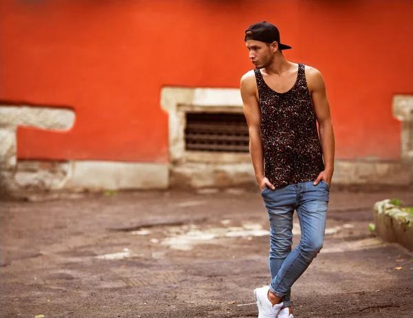 Hipster style guy. Fashion man standing near wall street orang — Stock Photo, Image