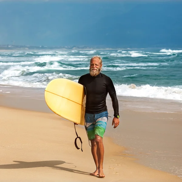Surfeur à la mer est debout avec une planche de surf couleur vive . — Photo