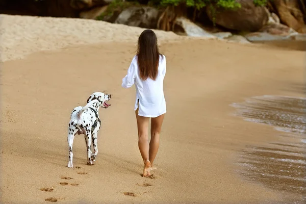 Mädchen spazieren am Strand mit dem Hund dalmatia — Stockfoto