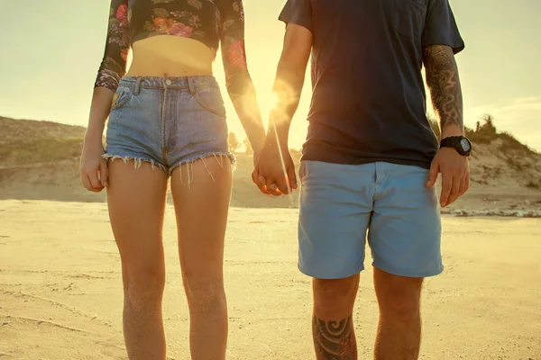 Pareja joven enamorada caminando en el parque de otoño tomados de la mano lo — Foto de Stock