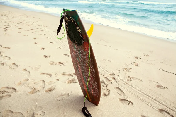 Surf board lies on the beach in the waves — Stock Photo, Image