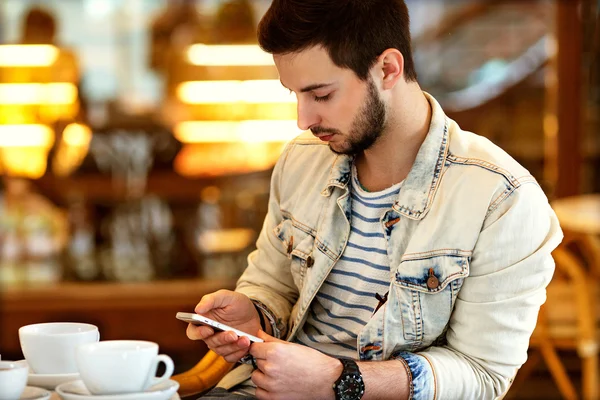 En man sitter på ett kafé med en telefon i handen, affärsmässighet, — Stockfoto