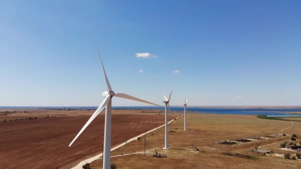 Veduta aerea delle turbine eoliche che generano energia eolica pulita tra i campi gialli. Produzione di energia rinnovabile nelle regioni delle steppe eoliche. — Video Stock