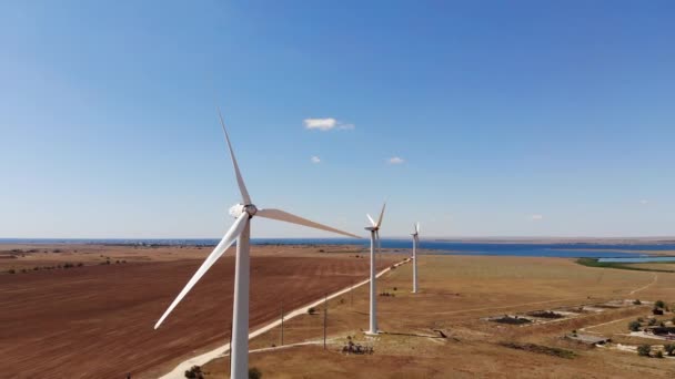 Aerial view of wind turbines generating clean wind power among yellow fields. Renewable energy production in wind-driven steppe regions. — Stock Video