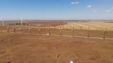 Rüzgar türbinlerinin hava görüntüsü sarı alanlar arasında temiz rüzgar enerjisi üretiyor. Rüzgârlı bozkırlarda yenilenebilir enerji üretimi.