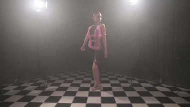 Güzel pembe elbiseli çekici genç kız profesyonel dansçı salon sporu sambu Latin Amerikalı dumanla dolu karanlık bir odada dans ediyor.