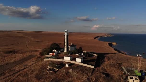 Un faro típico a rayas en la costa de la zona de la estepa por la noche. Vista aérea empinada de la costa — Vídeos de Stock