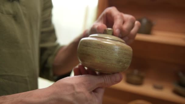Um oleiro masculino mostra seu trabalho Yixing bule de barro para uma cerimônia de chá artesanal nas proximidades. Profundidade de campo rasa — Vídeo de Stock