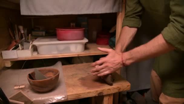 Man pottenbakker kneden klei verslaat het voor installatie op een pottenbakkerswiel — Stockvideo