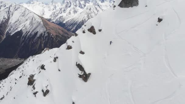 4K людина в повному зимовому альпіністському обладнанні, що спускається зі сніжного схилу з пішохідними полюсами в руці. Концепція середовища — стокове відео