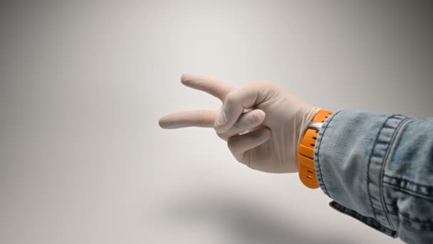 Una mano en un guante médico blanco sobre un fondo blanco muestra varios gestos con los dedos — Vídeo de stock