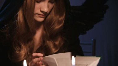 Siyah kapüşonlu, uzun saçlı ve kanatlı çekici bir kadının portresi karanlık bir odada oturur ve mum ışığında sihirli kitaplar okur. Sıkıcı kendini izole etme cadılar bayramı