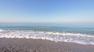 Sabahları mavi tonlarda ıssız bir sahil, kumlu sahilde küçük dalgalar akıyor. Denizin üstünde sis