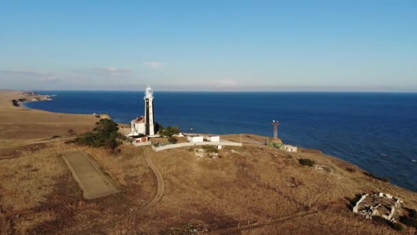 夕方には草原地帯の海岸にある典型的な縞模様の灯台。海岸の急な空中ビュー — ストック動画