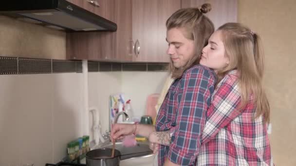 Νεαρό ζευγάρι άντρας και γυναίκα στην κουζίνα μαγειρεύουν μαζί και αγκαλιάζονται — Αρχείο Βίντεο