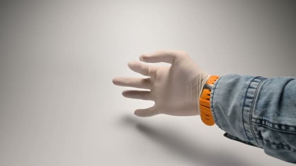 Eine Hand in einem weißen Medizinhandschuh auf weißem Hintergrund zeigt verschiedene Fingergesten — Stockvideo