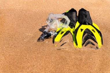 Şnorkel ve dalgıç yüzgeçli bir şnorkel takımı altın kumda yatar ve şeffaf açık deniz dalgası tarafından yıkanır. Boş zaman ve tatil konsepti