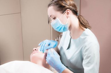 Profesyonel güzellik uzmanı bir güzellik salonundaki müşterisine botoks ya da hyaluronik asit enjekte eder.