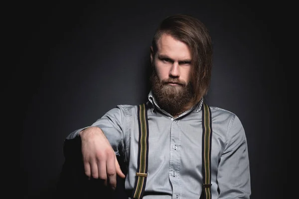 Atractivo hombre serio barbudo caucásico con estilo largo peinado. Estudio retrato contraste luz — Foto de Stock