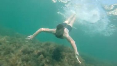 Sakallı, beyaz erkek, su altı ekipmanları olmadan daldı ve kameraya baktı.