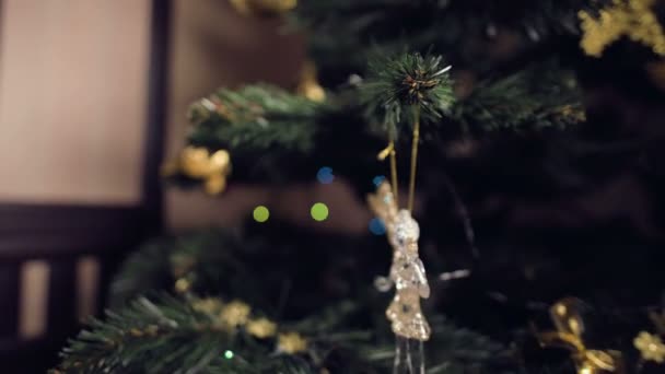 Närbild grunt skärpedjup av en liten flicka hand med en festlig manikyr hänger vackra leksaker på en konstgjord julgran — Stockvideo