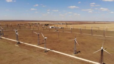 Rüzgar türbinlerinin hava görüntüsü sarı alanlar arasında temiz rüzgar enerjisi üretiyor. Rüzgârlı bozkırlarda yenilenebilir enerji üretimi.